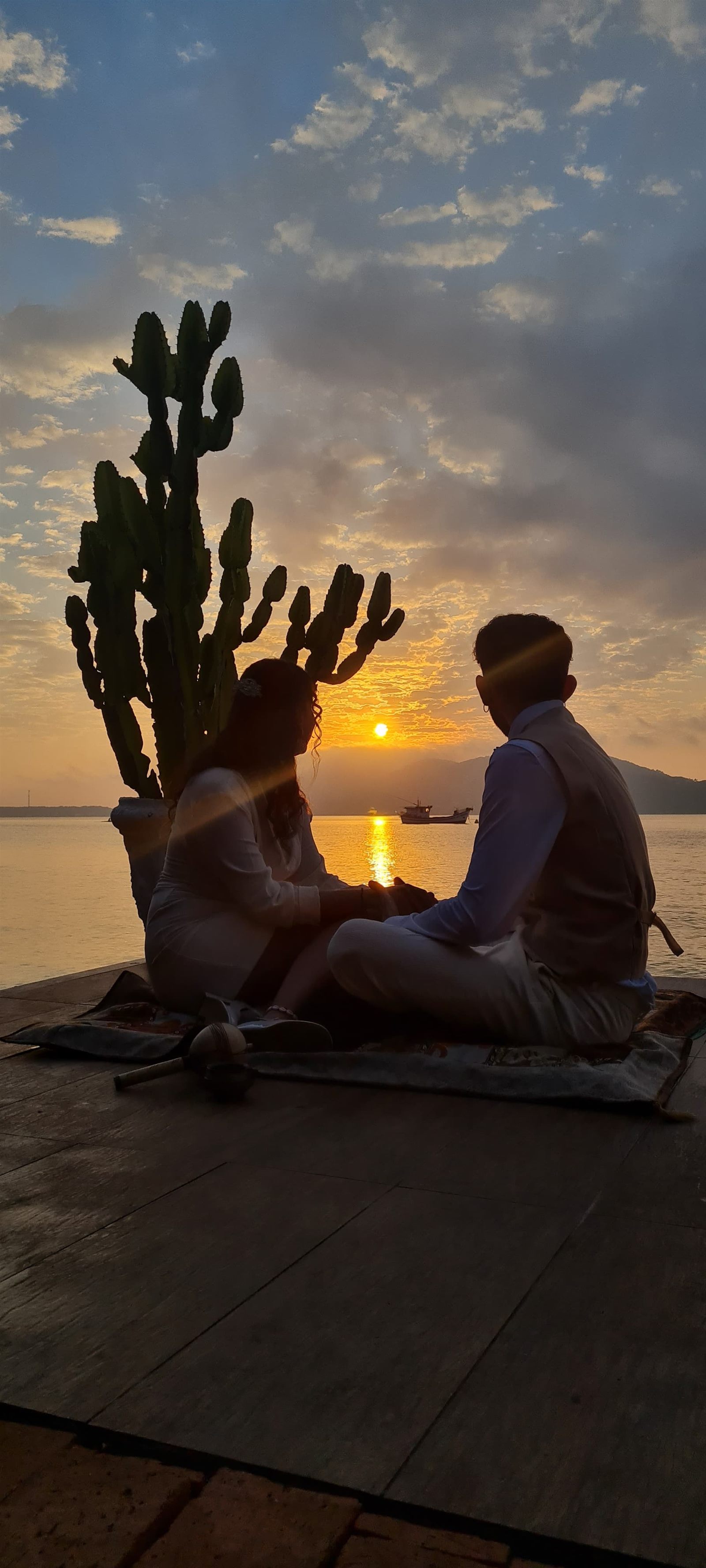 Casal ao pôr do sol no deck da Lagoa Nômade, com a lagoa ao fundo